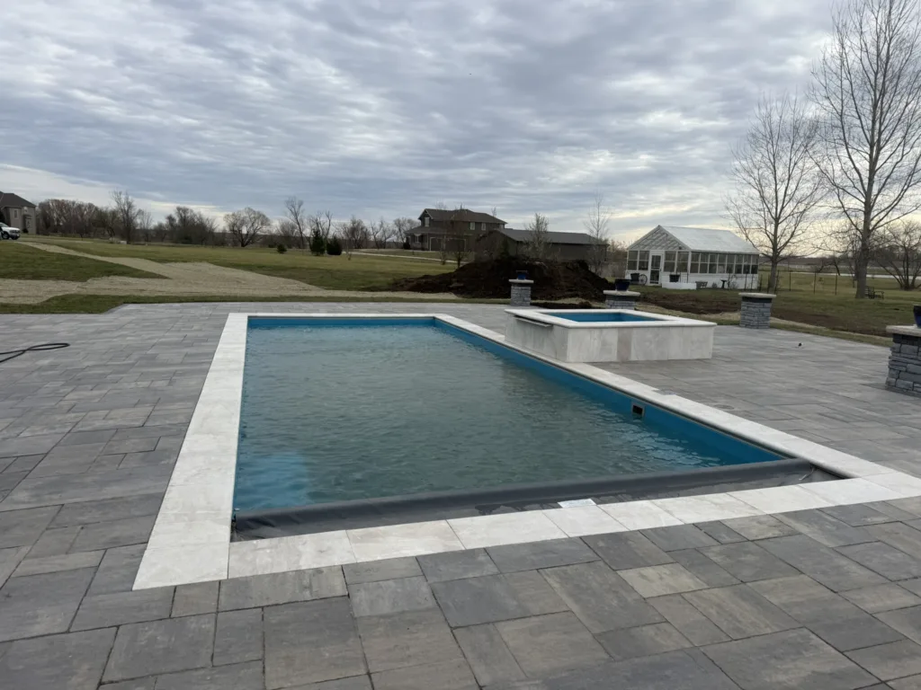 Pinnacle 40 rectangular fiberglass pool and spa with travertine coping and paver deck installed by Hometown Pool